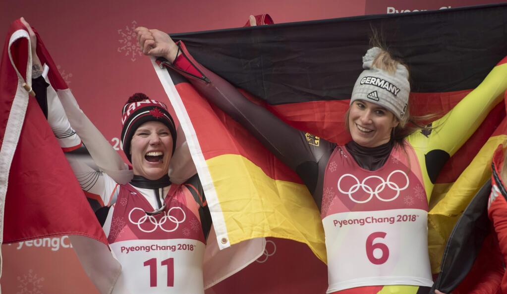 Canadian luger Alex Gough, left, celebrates winning a bronze medal as Natalie Geisenberger, of Germany, celebrates her gold medal win in women's luge at the 2018 Winter Olympics in Pyeongchang, South Korea, Tuesday, Feb. 13, 2018. (Jonathan Hayward/The Canadian Press via AP)