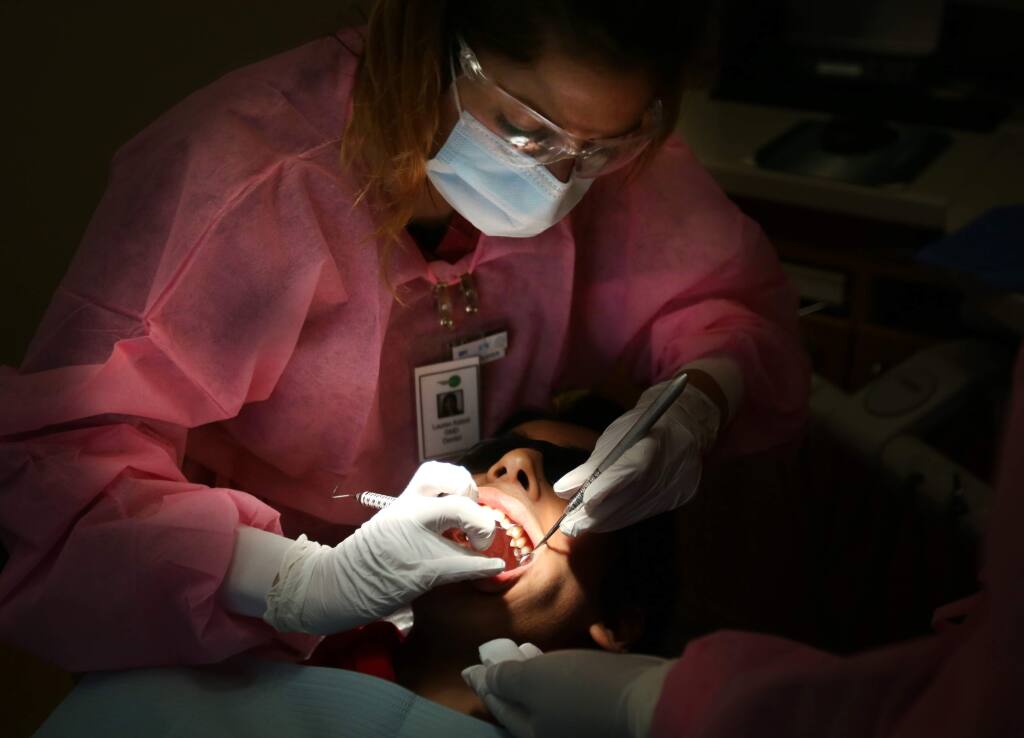 Lauren Katzel, a dentist at Petaluma Health Center, works on a patient in 2014. (Crista Jeremiason/ The Press Democrat)