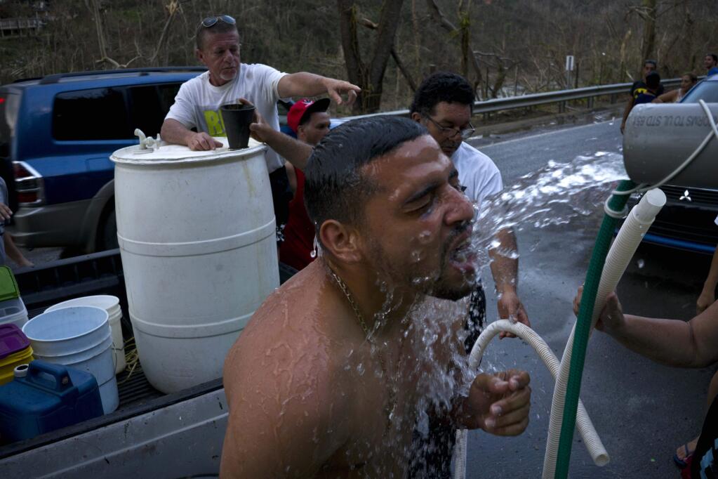 People affected by Hurricane Maria bathe in water piped from a creek in the mountains, in Naranjito, Puerto Rico, Thursday, Sept. 28, 2017. Residents of the area drive to the pipes to bathe because they were left without water supplies by the damage caused by Hurricane Maria. The pipe was set up by a neighbor who ran it from a creek in his property to the side of the road in order to help those left without water. (AP Photo/Ramon Espinosa)