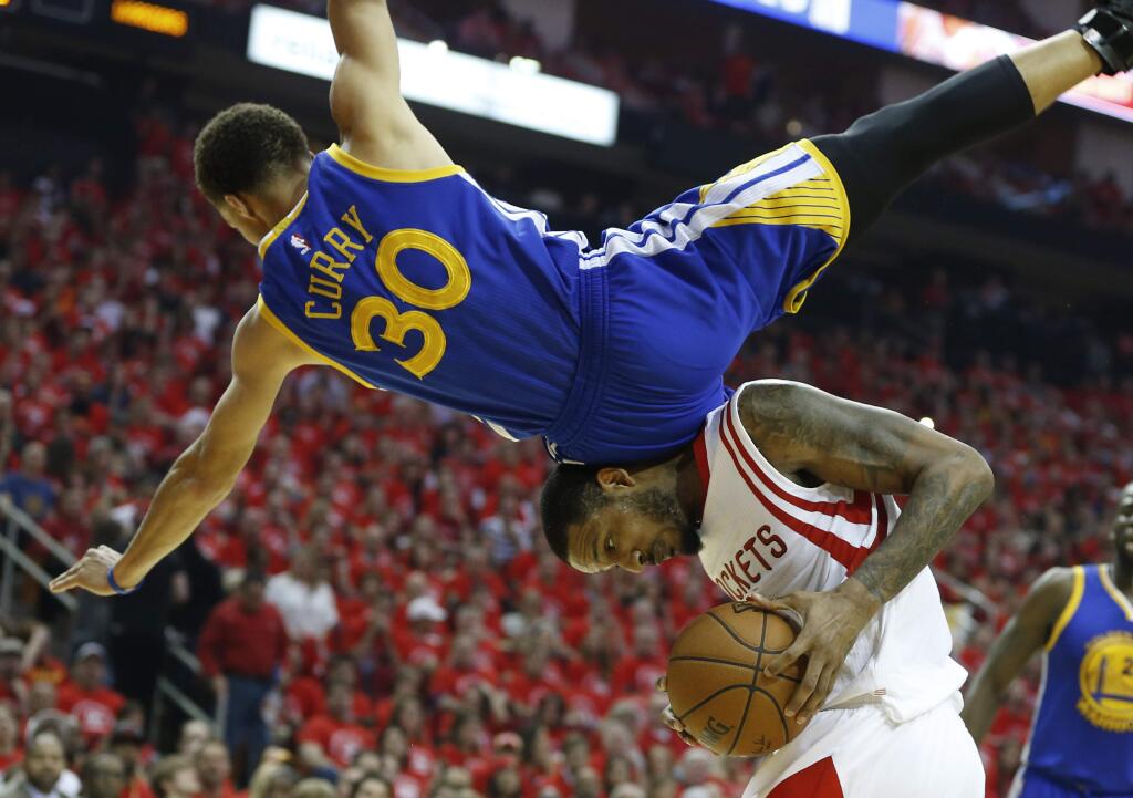 Golden State Warriors guard Stephen Curry (30) topples over Houston Rockets forward Trevor Ariza (1) during the first half in Game 4 of the Western Conference finals of the NBA basketball playoffs, Monday, May 25, 2015, in Houston. (James Nielsen/Houston Chronicle via AP) MANDATORY CREDIT