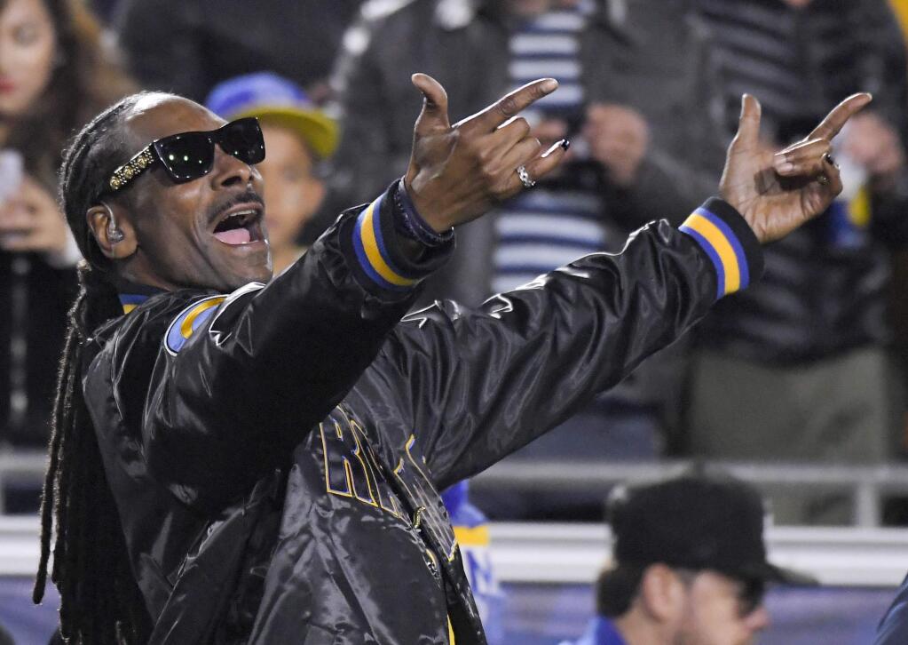 FILE - In this Jan. 6, 2018, file photo Snoop Dogg cheers during the first half of an NFL football wild-card playoff game between the Los Angeles Rams and the Atlanta Falcons in Los Angeles. Snoop Dogg says he has the back of a California high school basketball player suspended from her team for posting a photo of the rapper holding what appears to be a marijuana cigarette. The Fresno Bee reported Monday, Feb. 5, 2018, that the rapper urged the student's lawyers to contact his representatives. (AP Photo/Mark J. Terrill, File)