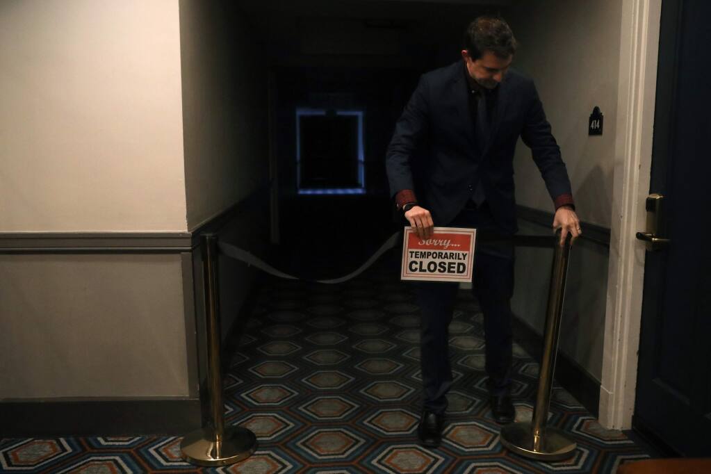 Hotel Petaluma general manager Dustin Groff adjusts a closed sign on a floor of the hotel that was temporarily closed on March 18, 2020, to save resources and money during the coronavirus pandemic. (BETH SCHLANKER/The Press Democrat)