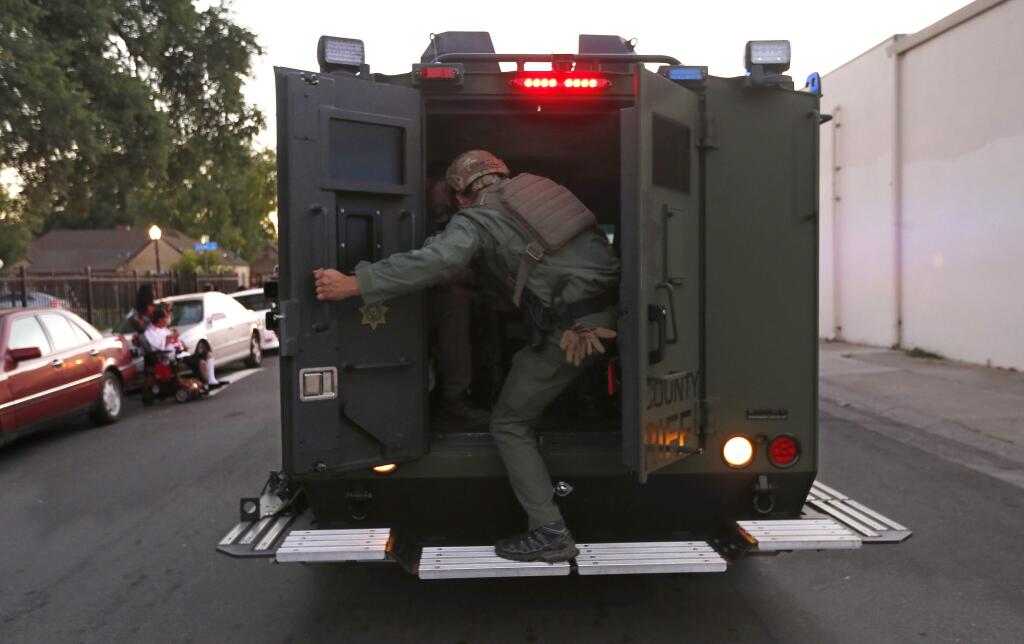 A law enforcement officer climbs into a tactical vehicle during a standoff with an armed suspect who has taken refuge after shooting a Sacramento police officer, Wednesday, June 19, 2019, in Sacramento, Calif. (AP Photo/Rich Pedroncelli)