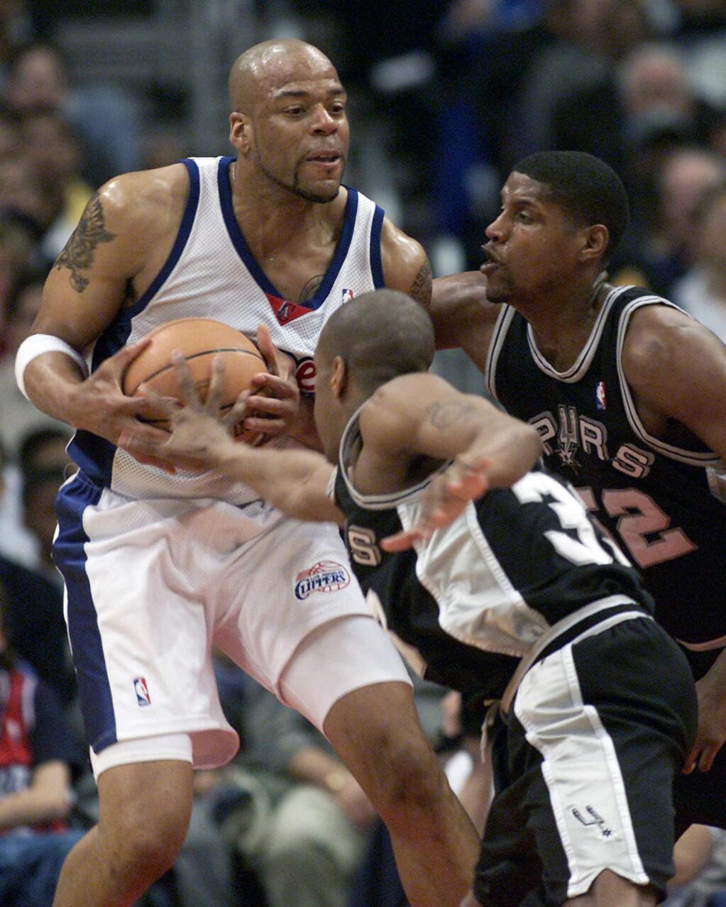 FILE - In this Saturday, April 7, 2001 file photo, Los Angeles Clippers' Sean Rooks fends off San Antonio Spurs defenders Antonio Daniels and Samaki Walker, right, during the first half of a basketball game in Los Angeles. Former NBA center and Philadelphia 76ers assistant coach Sean Rooks has died. He was 46. The team released a statement from Deborah Brown, the mother of Rooks, on Tuesday night, June 7, 2016. (AP Photo/Jill Connelly, File)