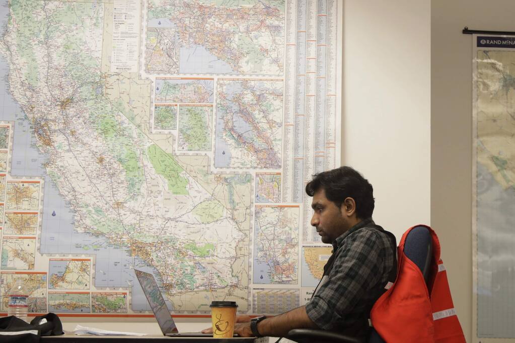 FILE - In this Oct. 10, 2019, file photo, Senior program analyst Siva Jasti works next to a map of California in the Pacific Gas & Electric (PG&E) Emergency Operations Center in San Francisco. The California Senate will investigate a California utility's process for cutting off power to more than 2 million people to prevent wildfires. In a memo to the Senate Democratic Caucus on Thursday, Oct. 17, 2019, Senate President Pro Tempore Toni Atkins asked the Senate Energy, Utilities, and Communications Committee to 'begin investigating and reviewing options to address the serious deficiencies' with PG&E's current process of shutting off power to prevent wildfires. (AP Photo/Jeff Chiu, File)