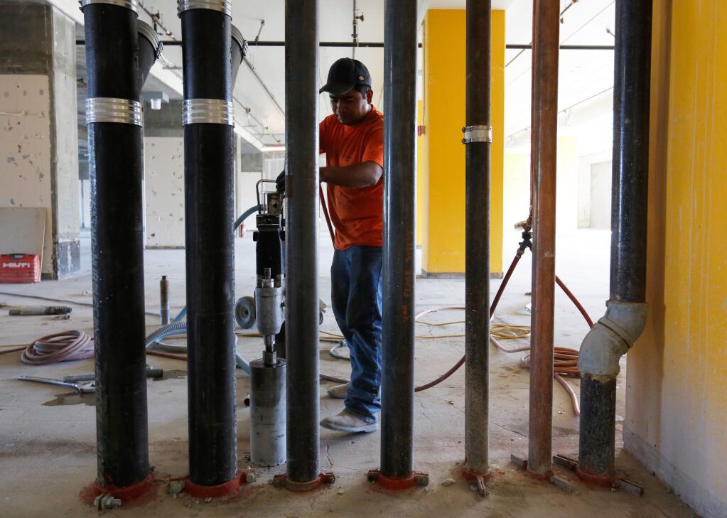 Vicente Ramirez of Durling Concrete Sawing sets a drill to bore pipe holes through the third floor, at the Museum on the Square building in Santa Rosa, California on Thursday, October 15, 2015. (Alvin Jornada / The Press Democrat)