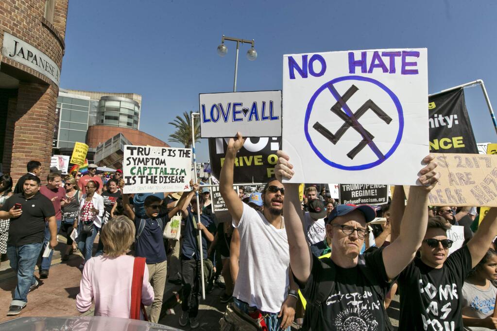 FILE--In this Aug. 13, 2017, file photo, demonstrators march in downtown Los Angeles decrying hatred and racism the day after a white supremacist rally that spiraled into violence in Charlottesville, Va. A monument at Hollywood Forever Cemetery commemorating Confederate veterans has been taken down after hundreds of people demanded its removal. (AP Photo/Damian Dovarganes, file)