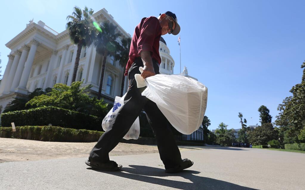 In this photo taken Tuesday, Aug. 12, 2014, plastic single-use bags are carried past the State Capitol in Sacramento. (AP Photo/Rich Pedroncelli)
