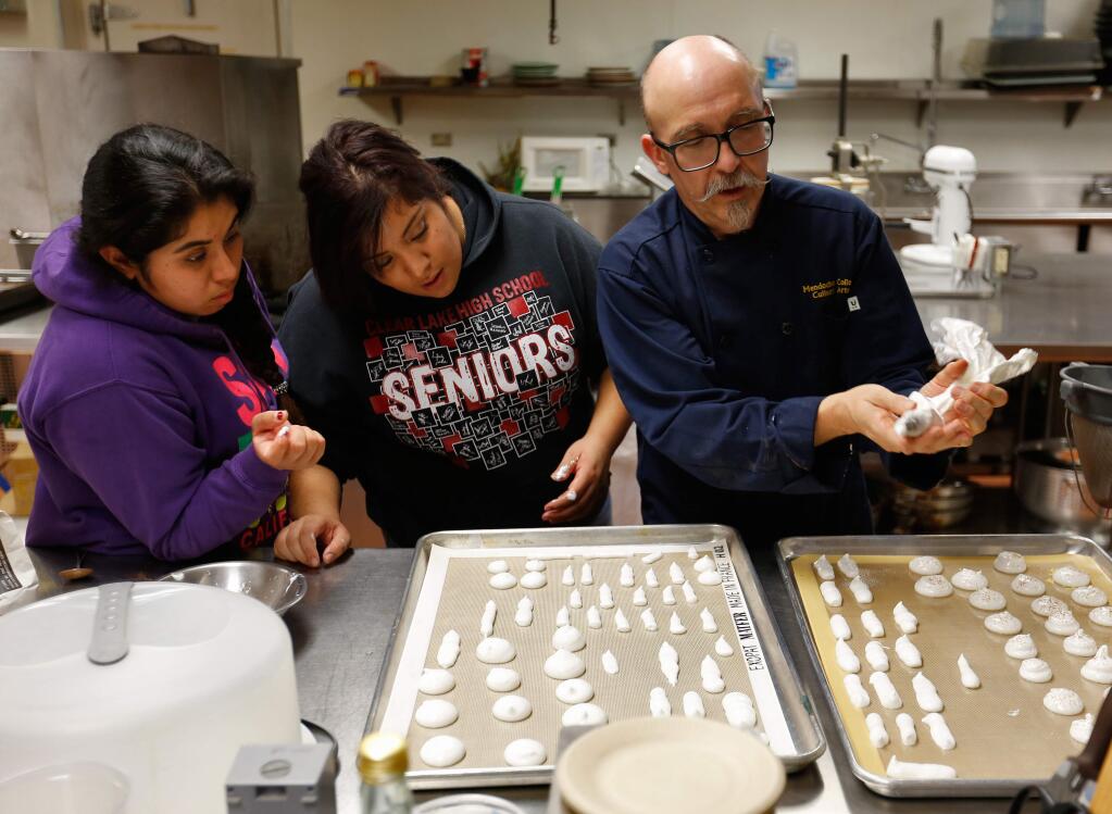 Chef Nicholas Petti, right, demonstrates how to pipe meringue onto baking sheets to students Maria Yanez, left, and Jennifer Hernandez during a culinary class at Mendocino College in Ukiah, California on Tuesday, November 24, 2015. (Alvin Jornada / The Press Democrat)