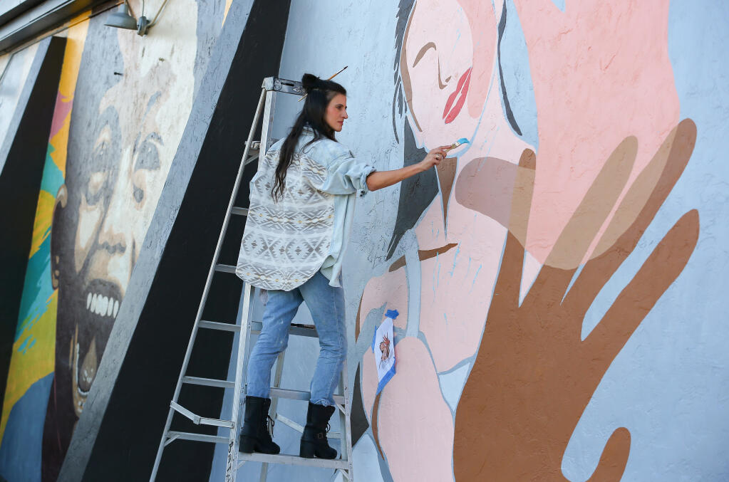 Artist Rachel Brooks works on a mural on the side of the Fulton Crossing Gallery building in Fulton on Thursday, October 29, 2020.  (Christopher Chung/ The Press Democrat)