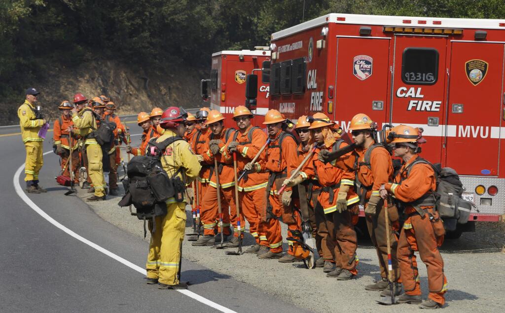 Prisoners from the McCain inmate crew from San Diego, Calif., prepare to clear brush from a road on Wednesday, Oct. 11, 2017 in Calistoga, Calif. Authorities are looking for an inmate firefighter who walked away while assigned to a crew working on the remnants of a Southern California wildfire. (AP Photo/Ben Margot)