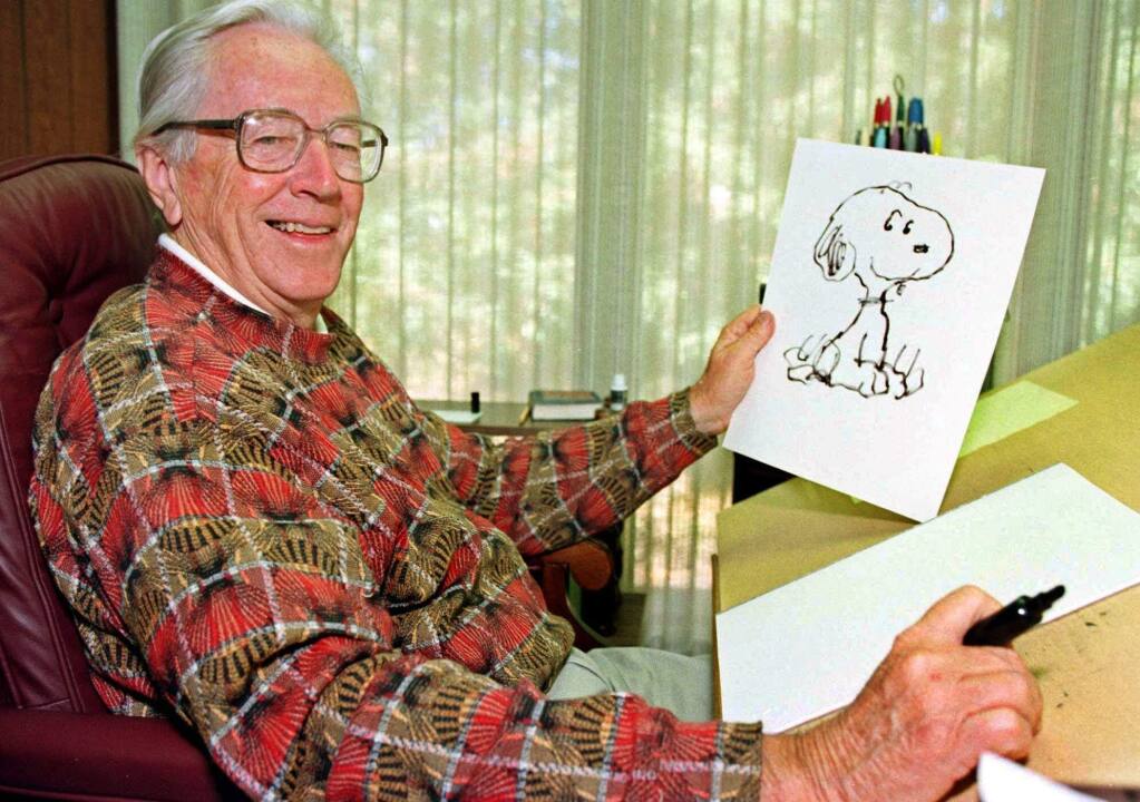 FILE - In this Feb. 12, 2000, file photo, cartoonist Charles Schulz displays a sketch of his beloved character 'Snoopy' in his office in Santa Rosa, Calif. The home of “Peanuts” creator Schulz burned to the ground in the deadly California wildfires but his widow escaped, her stepson said Thursday, Oct. 12, 2017. Jean Schulz, 78, evacuated before flames engulfed her hillside home Monday and is staying with a daughter, Monte Schulz said. (AP Photo/Ben Margot, File)