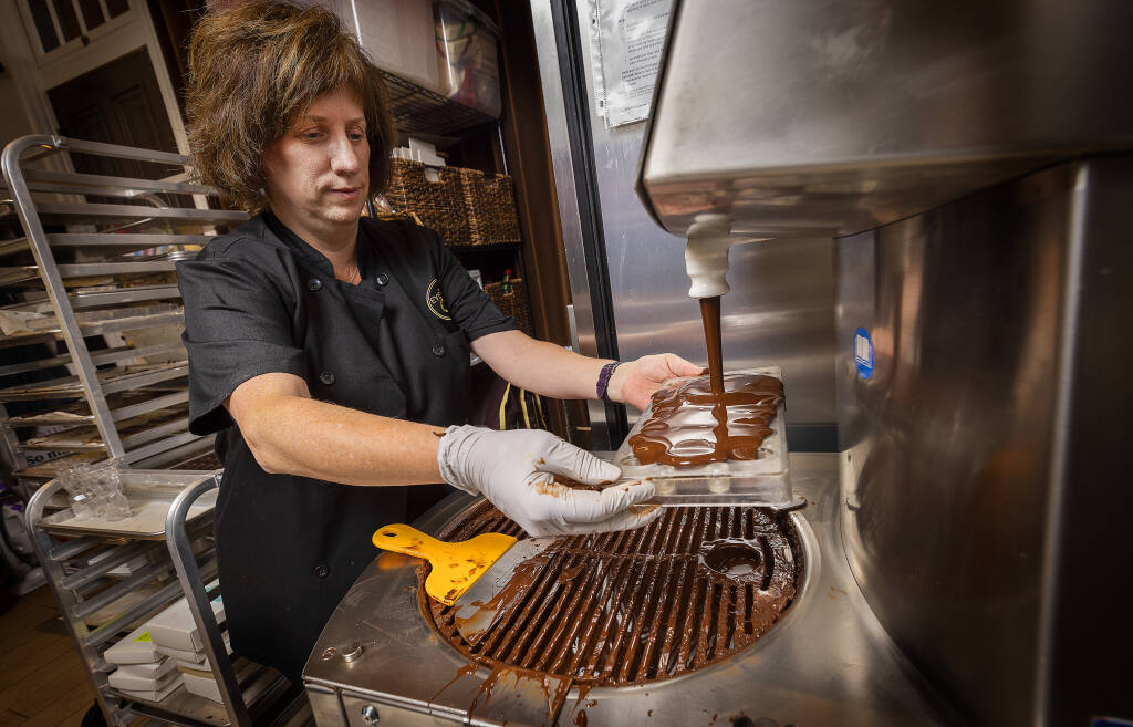 Eye Candy co-owner Jill McLewis fills trays of chocolates in their Sebastopol kitchen, Tuesday, Oct. 18, 2022.  (John Burgess/The Press Democrat)
