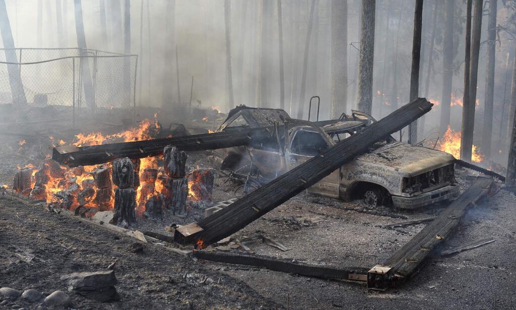 A burned truck and smoldering ruins is all that is left of a garage near a house that burned on Cedar Drive in Oakhurst, Calif., Sunday, Sept. 14, 2014, as two raging wildfires in the state forced hundreds of people to evacuate their homes. (AP Photo/The Fresno Bee, Mark Crosse)