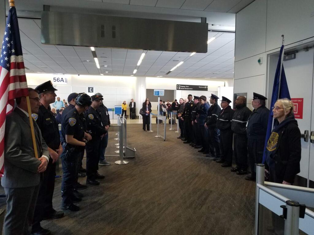 Firefighters and police officers are present at San Francisco International Airport to escort the remains of helicopter pilot Jennifer Topper. (Zach Brown)