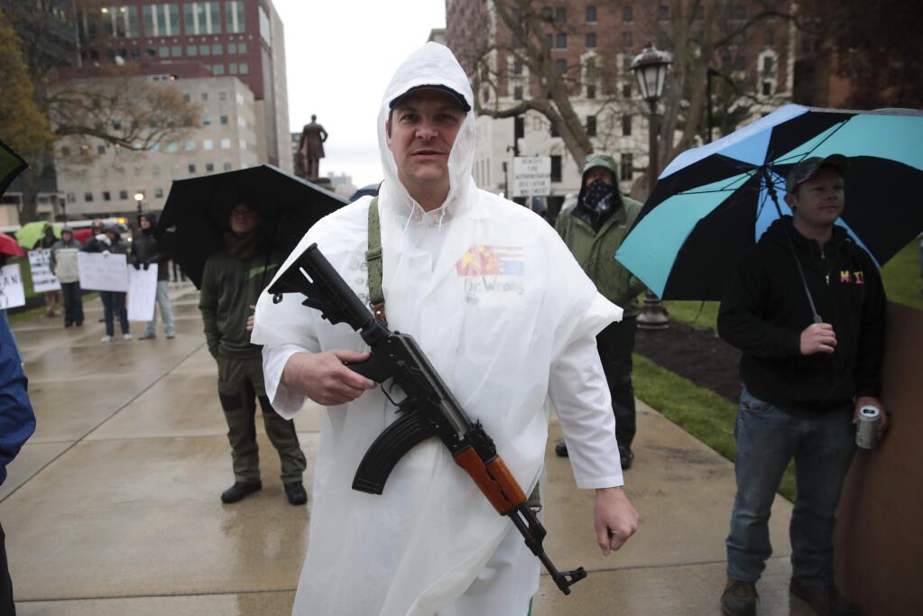 A protester carries his rifle during a rally against Michigan's coronavirus stay-at-home order at the State Capitol in Lansing, Mich., Thursday, May 14, 2020. (AP Photo/Paul Sancya)