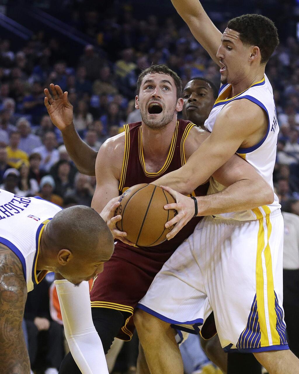 Cleveland Cavaliers' Kevin Love looks to pass away from Golden State Warriors' Klay Thompson, right, and Marreese Speights, left, during the first half of a game Friday, Jan. 9, 2015, in Oakland. (AP Photo/Ben Margot)