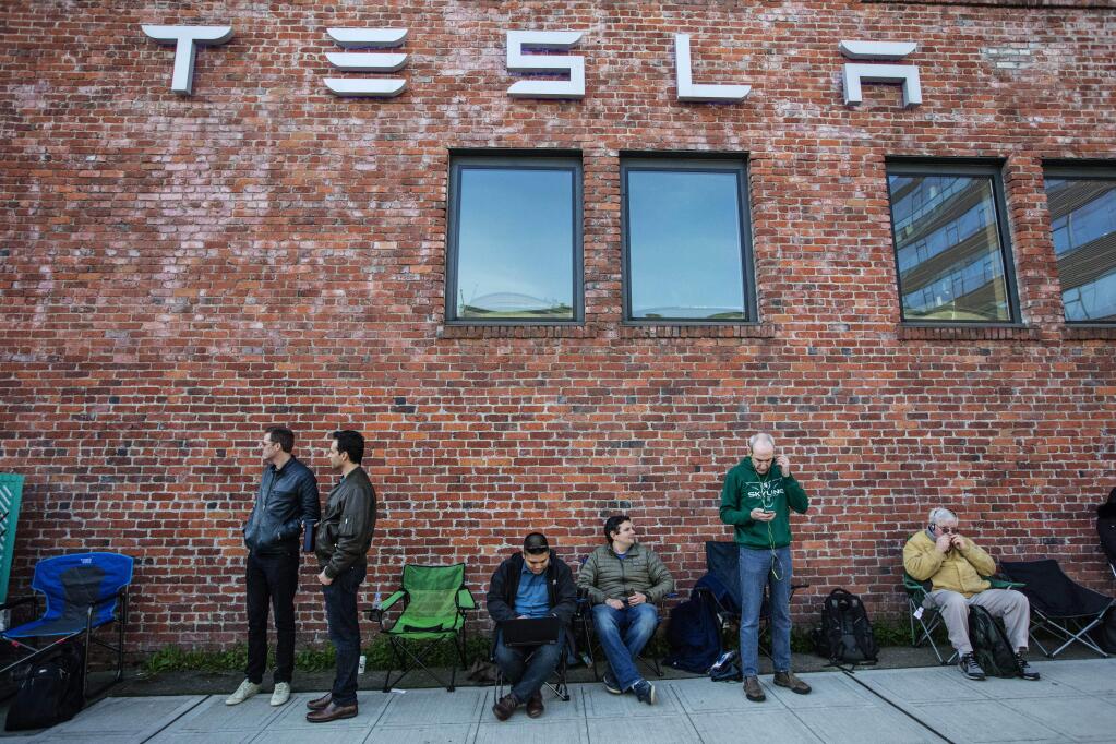 FILE - In this March 31, 2016 file photo, people wait in line to preorder the new Tesla in South Lake Union, Thursday, March 31, 2016, in Seattle. More than 276,000 people pre-order the Tesla Model 3 in less than a week. Is it the Tesla phenomenon, or has the $35,000 electric car with a range of 200-plus miles taken finally taken the electric car to the masses.. (Steve Ringman/The Seattle Times via AP)