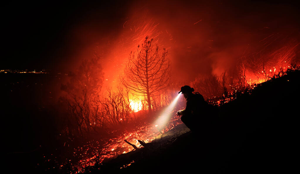 Northern Sonoma County Fire captain Carlos Mendez stands lookout as firefighter make access to the Geyser fire, located at the very top of Geyser Peak above Alexander Valley, during a windstorm with gusts near 80 mph, early Saturday morning, Jan. 22, 2022. (Kent Porter / The Press Democrat) 2022