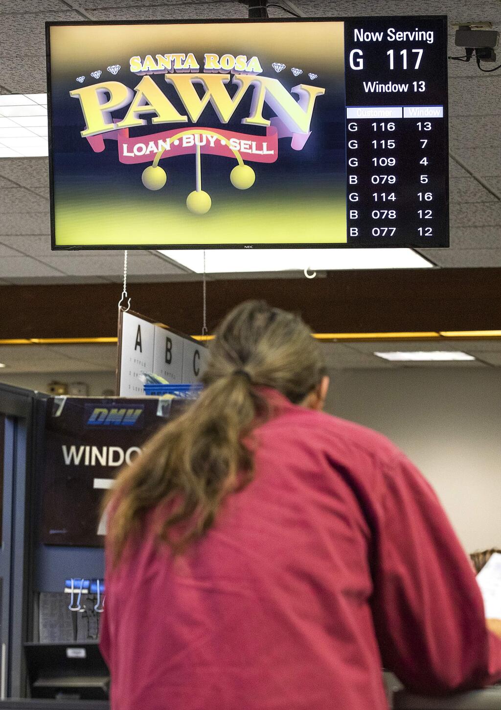 The Motor Vehicle Network, a non-governmental business, brings in hundreds of thousands of dollars for advertising next to customer numbers on television screens at DMV offices across the state including the Santa Rosa office. (photo by John Burgess/The Press Democrat)