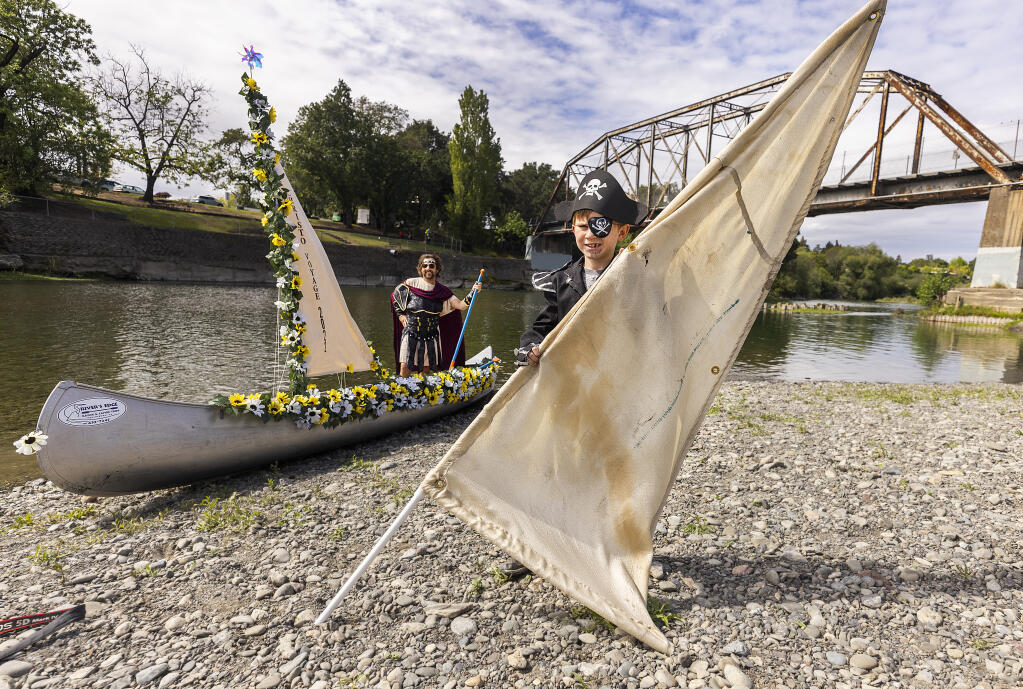 River’s Edge Kayak & Canoe Trips owner Dave Lockhart tests out a canvas sail on his canoe on the Russian River in Healdsburg on Friday, April 15, 2022. His son Jack, 9, holds a piece of fabric used in Christo’s “The Running Fence,” which Lockhart hopes to use on his canoe during a 5-day “Voyage” to Jenner in May.  (John Burgess/The Press Democrat)
