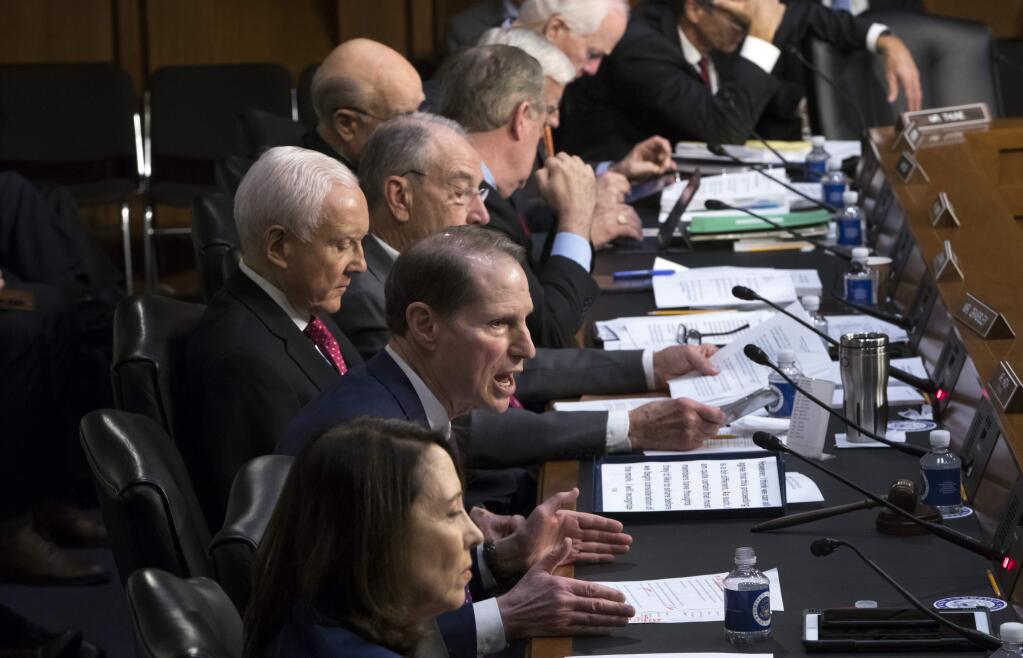 Sen. Ron Wyden, D-Ore., center, the top Democrat on the Senate Finance Committee, criticizes the Republican tax reform plan while Chairman Orrin Hatch, R-Utah, left, and GOP members, top, listen to his opening statement as the panel begins work overhauling the nation's tax code, on Capitol Hill in Washington, Monday, Nov. 13, 2017. The legislation in the House and Senate carries high political stakes for President Donald Trump and Republican leaders in Congress, who view passage of tax cuts as critical to the GOP's success at the polls next year. (AP Photo/J. Scott Applewhite)