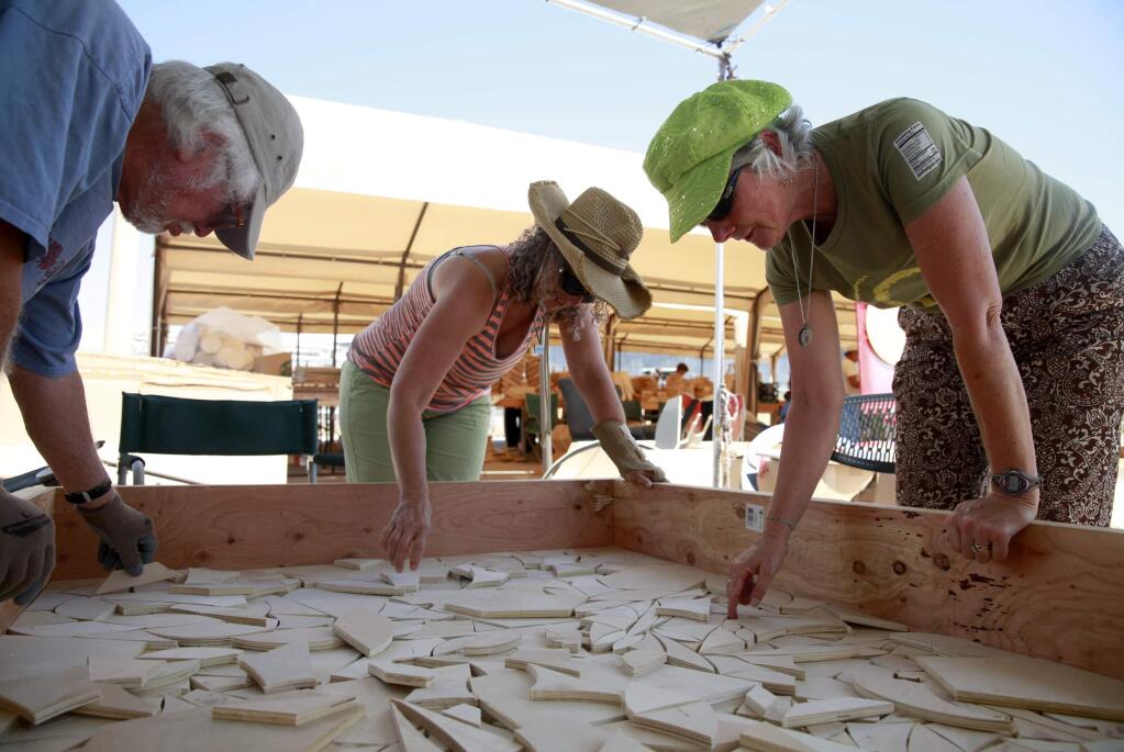 (From left)John Mueller, Ellen Gordon, and Anila Roberts put together wooden pieces for a mosaic floor of a wooden temple which will be constructed at Burning Man, on Thursday, July 24, 2014 in Petaluma, California. (BETH SCHLANKER/ The Press Democrat)