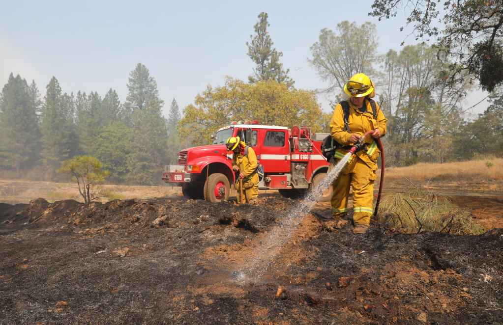 Hopland Fire District firefighters Daisy Smith, right, and Albert Farrens put out hotspots along Friesen Road near  Angwin on Tuesday, September 29, 2020.  (Christopher Chung/ The Press Democrat)
