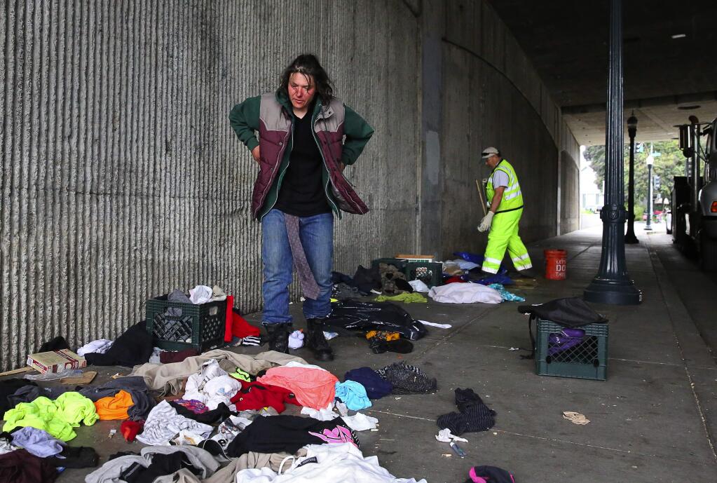 Dyan Jones stands over an assortment of clothing as she looks for necessities, while City of Santa Rosa public works personnel clean up the homeless encampment from the Sixth Street underpass, at Morgan Street, in Santa Rosa, on Wednesday, Feb. 1, 2017. (Christopher Chung/ The Press Democrat)
