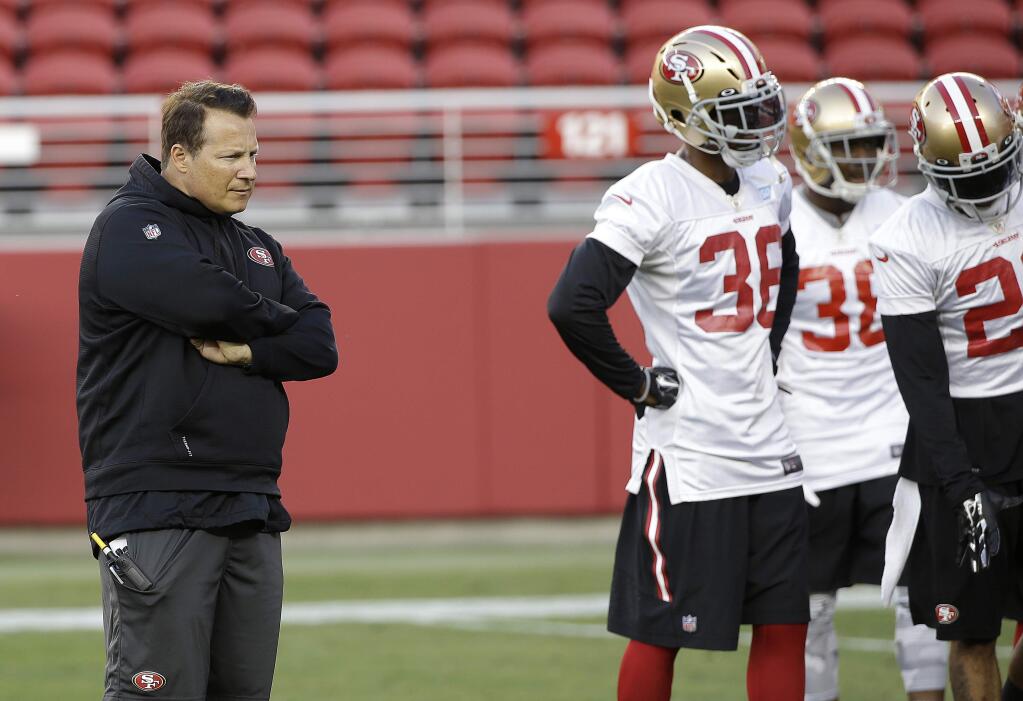 In this Aug. 1, 2015, file photo, San Francisco 49ers defensive coordinator Eric Mangini, left, watches during NFL football training camp in Santa Clara. (AP Photo/Jeff Chiu, File)