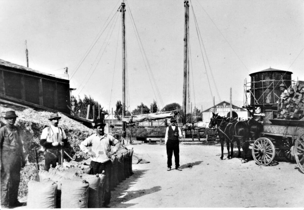 Gunerius "George" Aanunsen (center) and Pete Aaununsen (aboard wagon) at their supply yard beside the D Street Bridge, 1906 (Petaluma Historical Library & Museum)