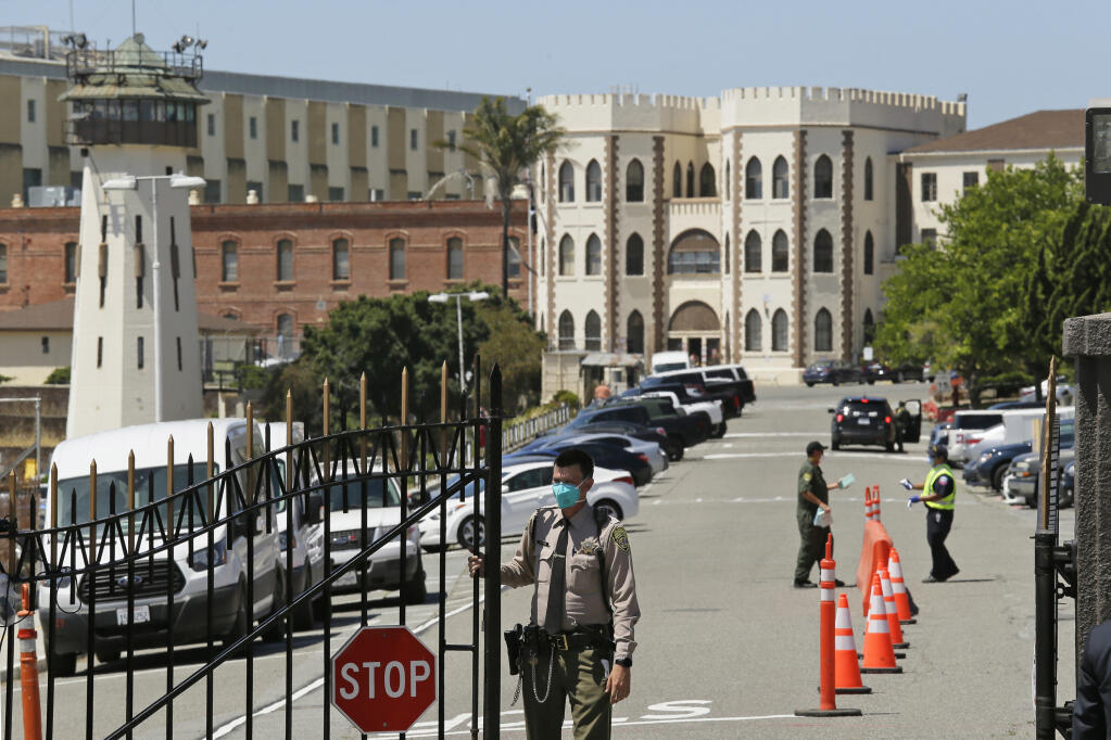 FILE - In this July 9, 2020, file photo, a correctional officer closes the main gate at San Quentin State Prison in San Quentin, Calif. (AP Photo/Eric Risberg, File)