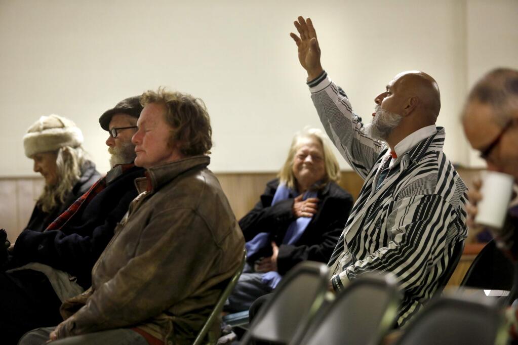 Daniel Magdaleno, right, raises his hand in prayer during a memorial service for the homeless who have died in the past 22 months hosted by the Metropolitan Community Church of the Redwood Empire at Odd Fellows Hall in Guerneville, on Sunday, January 21, 2018. (BETH SCHLANKER/ The Press Democrat)