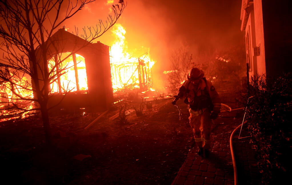 A firefighter changes defensive position as he protects a home from burning on Mountain Hawk Drive in Santa Rosa's Skyhawk Community as the Glass fire rolls in from Napa County, Monday morning, Sept. 28, 2020. (Kent Porter / The Press Democrat) 2020