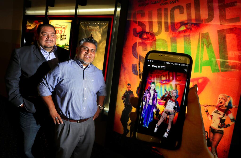 Fuze Viewer founder Rick Vegaz, left, and marketing director Danny Martinez with their app that allows the viewer to see movie trailers and characters when pointed at posters or art from the movie. (JOHN BURGESS/The Press Democrat)