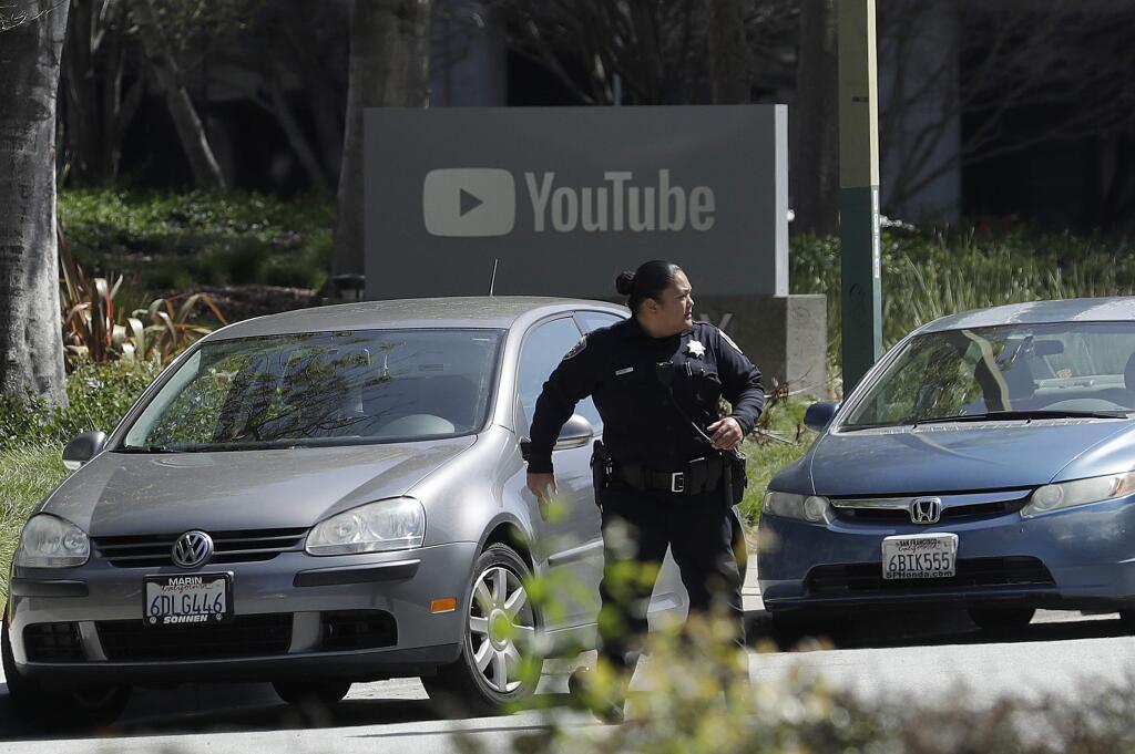 An officer runs past a YouTube sign near the company's complex in San Bruno, Calif., Tuesday, April 3, 2018. A woman opened fire at YouTube headquarters Tuesday, setting off a panic among employees and wounding several people before fatally shooting herself, police and witnesses said. (AP Photo/Jeff Chiu)