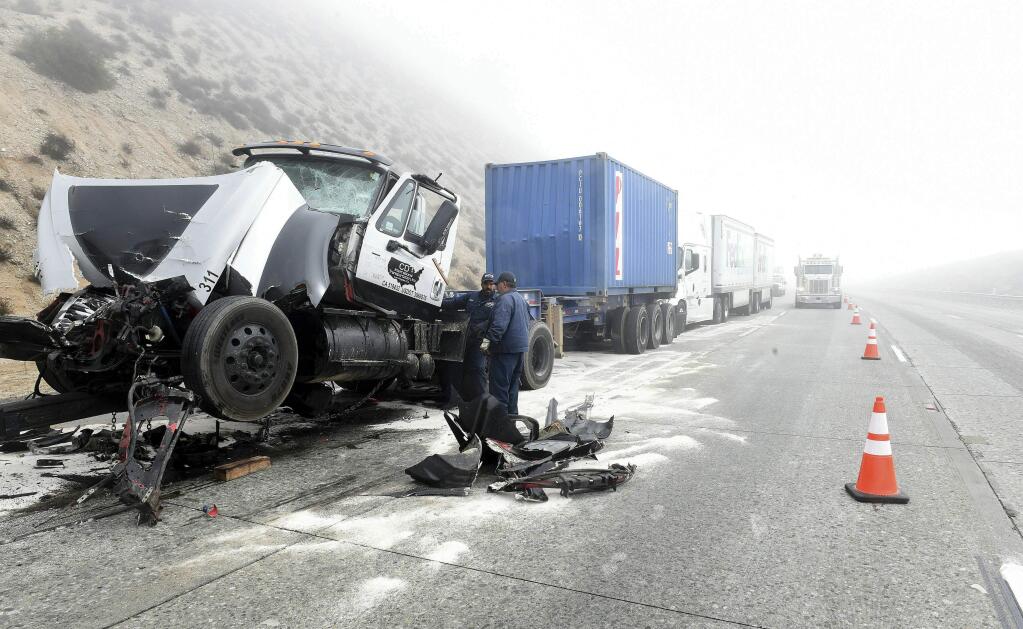 Crews work to clear the roadway after a multi-vehicle collision along a foggy Interstate 15 in the Cajon Pass near Hesperia Calif., Wednesday Jan. 16, 2019. (Will Lester/The Orange County Register via AP)