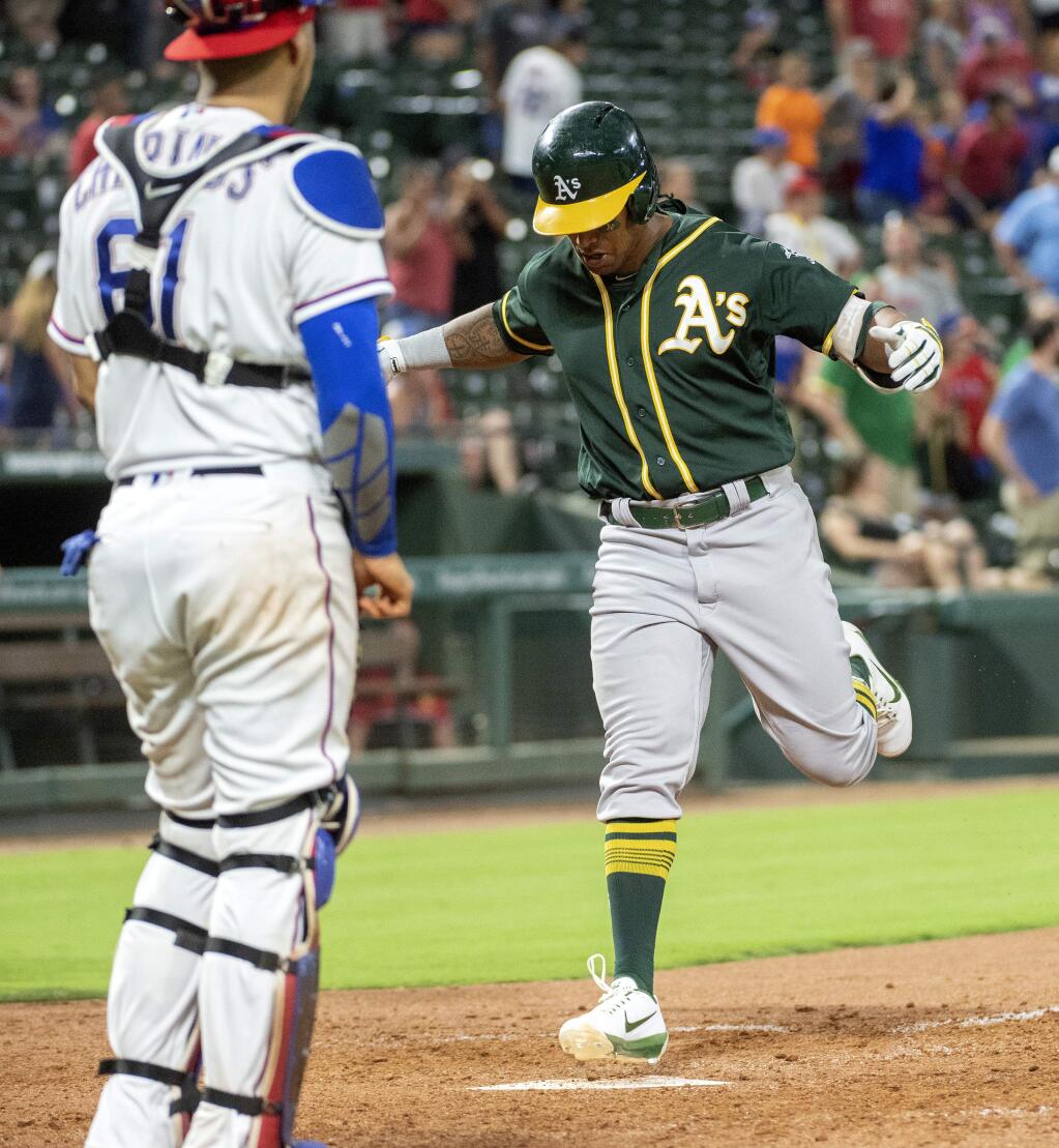 The Oakland Athletics' Khris Davis crosses the plate on a go-ahead two-run home run off Texas Rangers relief pitcher Jose Leclerc, as Rangers catcher Robinson Chirinos stands nearby, during the ninth inning Wednesday, July 25, 2018, in Arlington, Texas. Oakland won 6-5. (AP Photo/Jeffrey McWhorter)