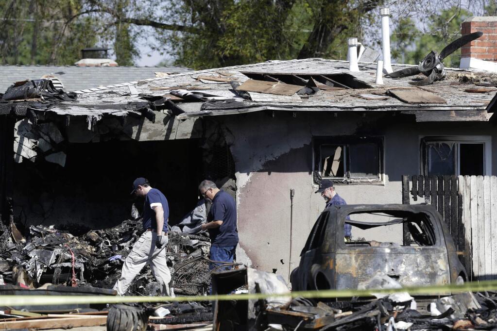 Investigators search the scene of a small plane crash in Riverside, Calif. on Tuesday, Feb. 28, 2017. A small plane carrying people home from a cheerleading competition slammed into two homes and started a raging fire, authorities and witnesses said. The twin-engine plane with five occupants crashed late Monday, Feb. 27, in a Riverside neighborhood after taking off from a nearby airport and making it less than a mile, Riverside Fire Chief Michael Moore said. It was bound for San Jose.(AP Photo/Nick Ut)