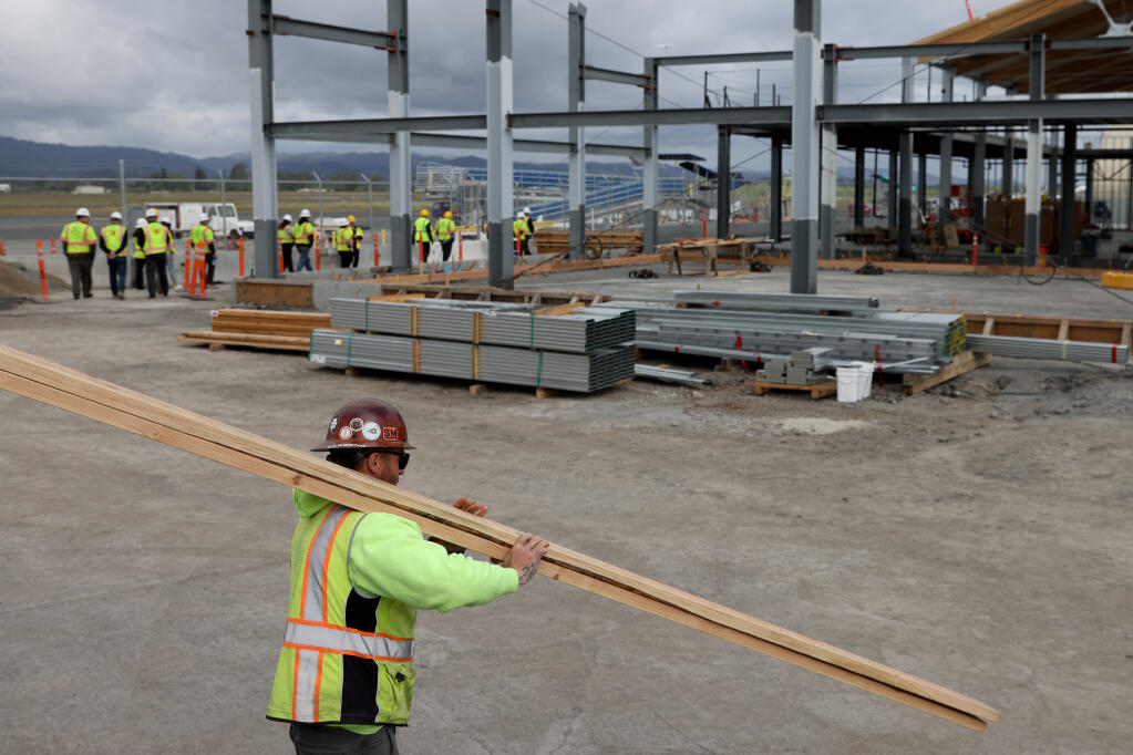 Ghilotti Bros. employee Billy Petrie carries lumber onsite as  local officials and airline employees tour the new terminal expansion and modernization project at the Charles M. Schulz Sonoma County Airport in Santa Rosa, Calif., on Wednesday, April 13, 2022.(Beth Schlanker/The Press Democrat)