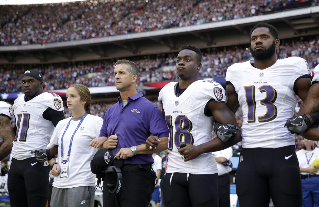Baltimore Ravens head coach John Harbaugh, center left, links arms with his daughter Alison and wide receiver Jeremy Maclin (18) during the playing of the U.S. national anthem before an NFL football game against the Jacksonville Jaguars at Wembley Stadium in London, Sunday Sept. 24, 2017. Also pictured are Breshad Perriman (11) and Chris Matthews (13). (AP Photo/Matt Dunham)
