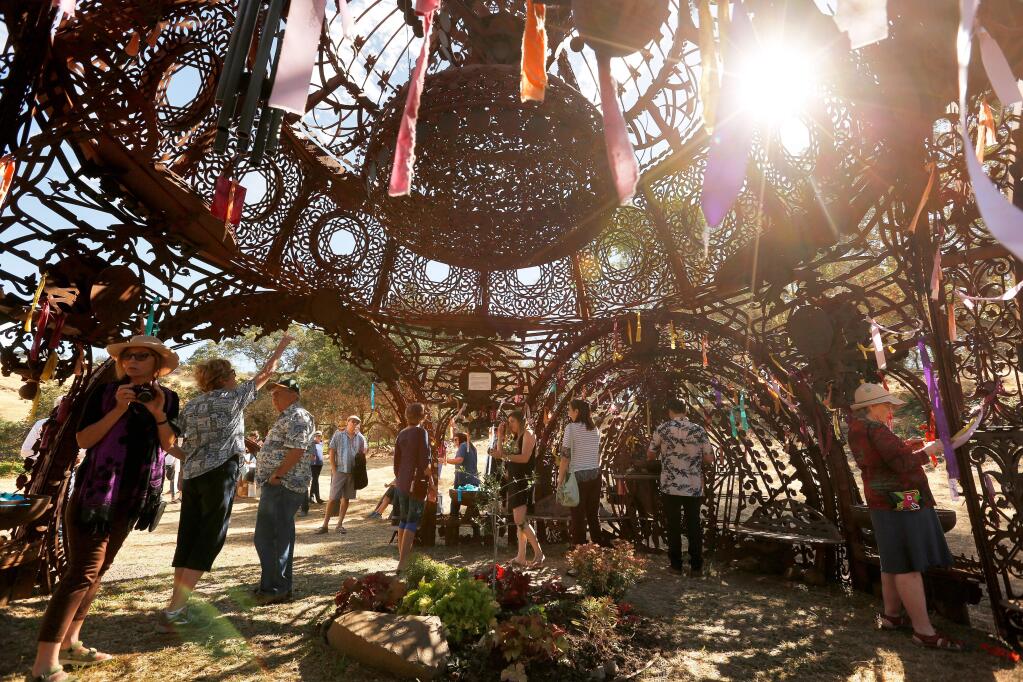 Guests meander through the Temple of Remembrance, one of the art installations at Paradise Ridge Winery's sculpture garden, where names of loved ones who recently passed on can be written on colorful ribbons and tied to the structure, during the reopening of the sculpture garden at Paradise Ridge Winery in Santa Rosa, California, on Saturday, July 7, 2018. (Alvin Jornada / The Press Democrat)