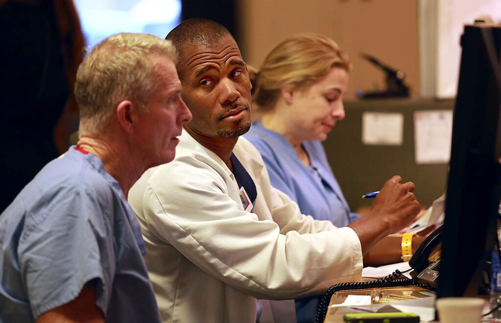 Dr. Abdul Harris, center, the chairman of the Memorial Hospital surgery department hears reports on the status of post-surgery patients from nurse practitioners, Tim Dillon, left, and Gina Bey. (photo by John Burgess/The Press Democrat)