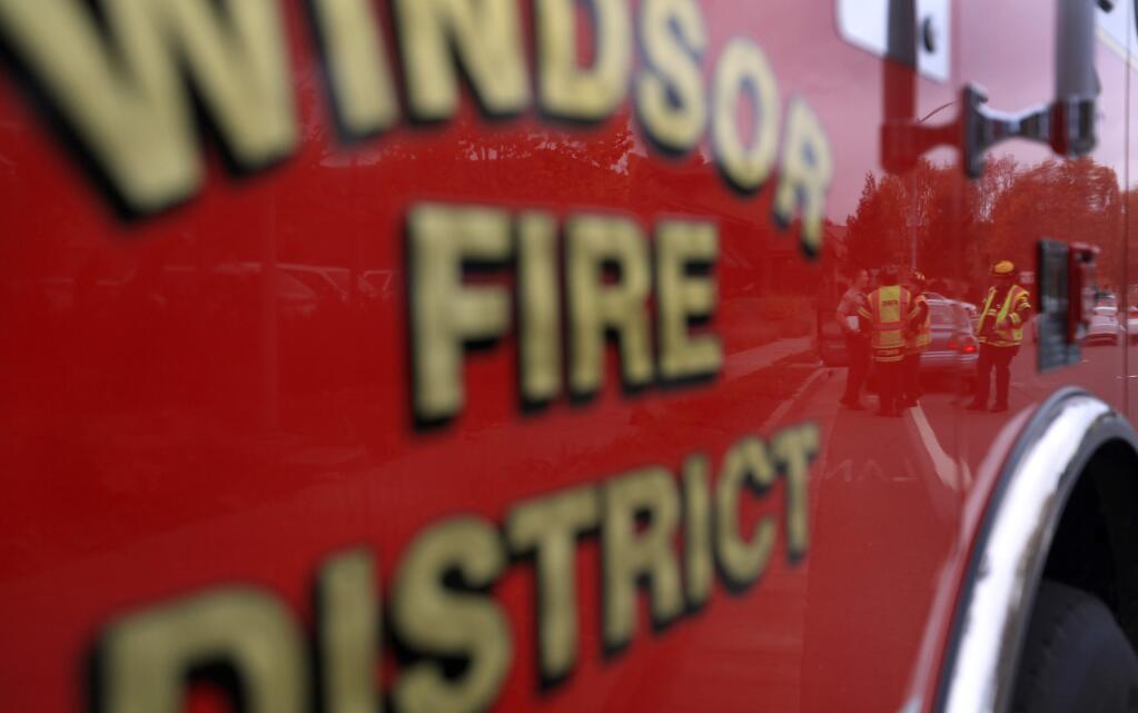 Windsor firefighters are reflected in their rig at a vehicle accident, Friday Nov. 29, 2014 in Windsor. (Kent Porter / Press Democrat) 2014