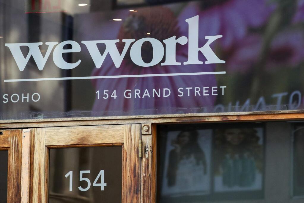 FILE - This Oct. 15, 2019, file photo shows a WeWork logo at the entrance to one of their office spaces in the SoHo neighborhood of New York. WeWork is slashing nearly 20% of its work force in the wake of its failed stock market debut. The shared-office company said it has laid off 2,400 of its approximately 12,500 employees to “create a more efficient organization.” (AP Photo/Mary Altaffer, File)