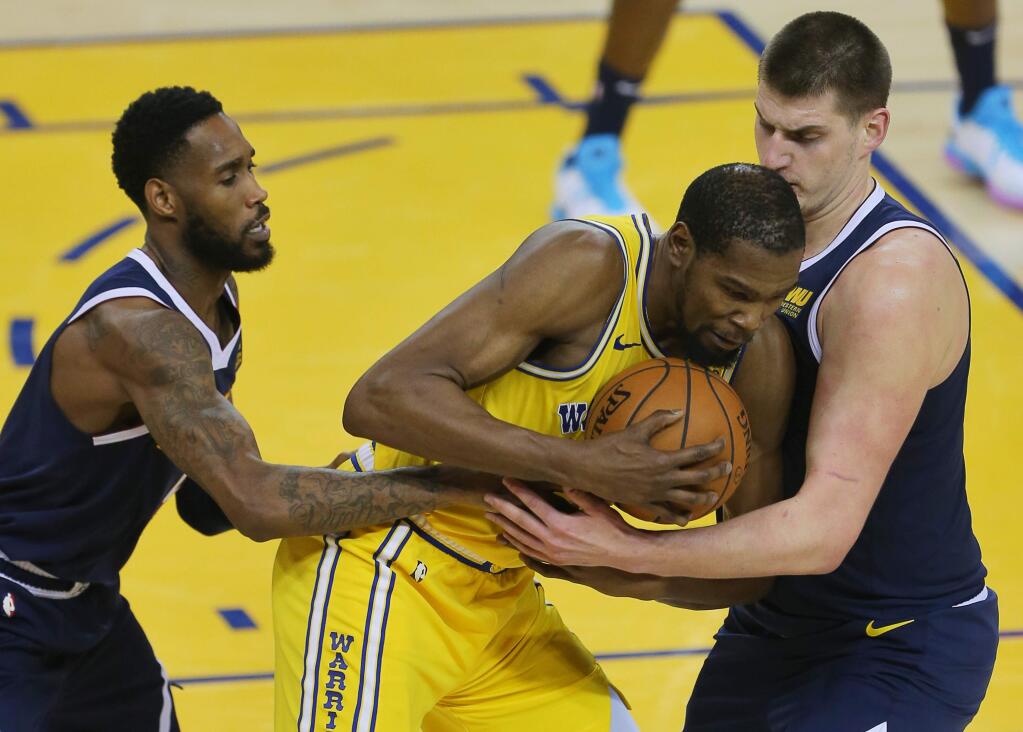 Warriors forward Kevin Durant fights his way out of a double-team by Denver Nuggets guard Will Barton, left, and Denver Nuggets center Nikola Jokic during their game in Oakland on Tuesday, April 2, 2019. (Christopher Chung/ The Press Democrat)