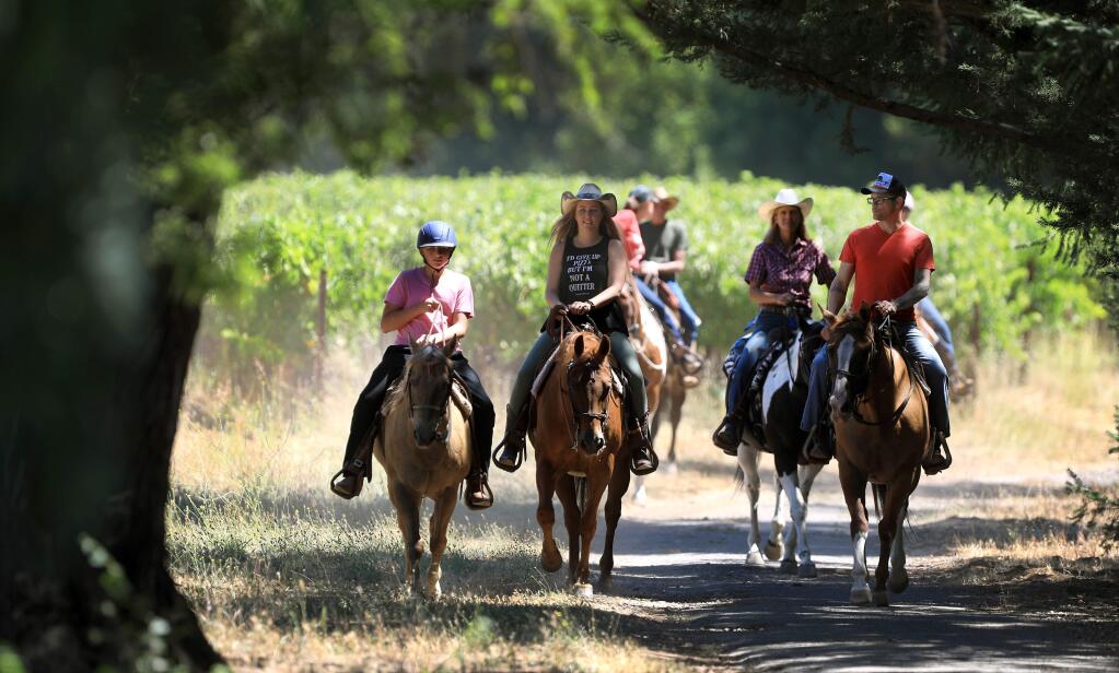 Aiden, 12, Erica and Josh Hartwig, of Florida, finish a trail ride led by Michelle Rogers of Sonoma Valley Trail through vineyards around Bartholomew Estate Winery in Sonoma, Friday, Aug. 2, 2019. (Kent Porter / The Press Democrat) 2019