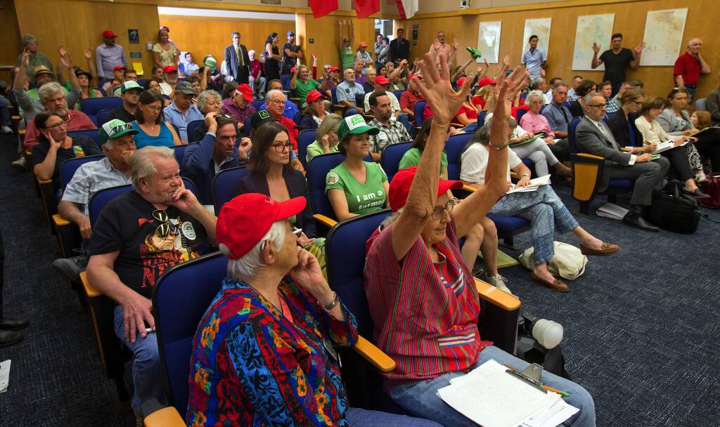 Supporters of marijuana farmers, wearing green, and opponents of marijuana grows in their neighborhoods, in red, filled the Sonoma County Supervisors chambers and the hallway outside for a meeting on changes to cannabis policies. (photo by John Burgess/The Press Democrat)