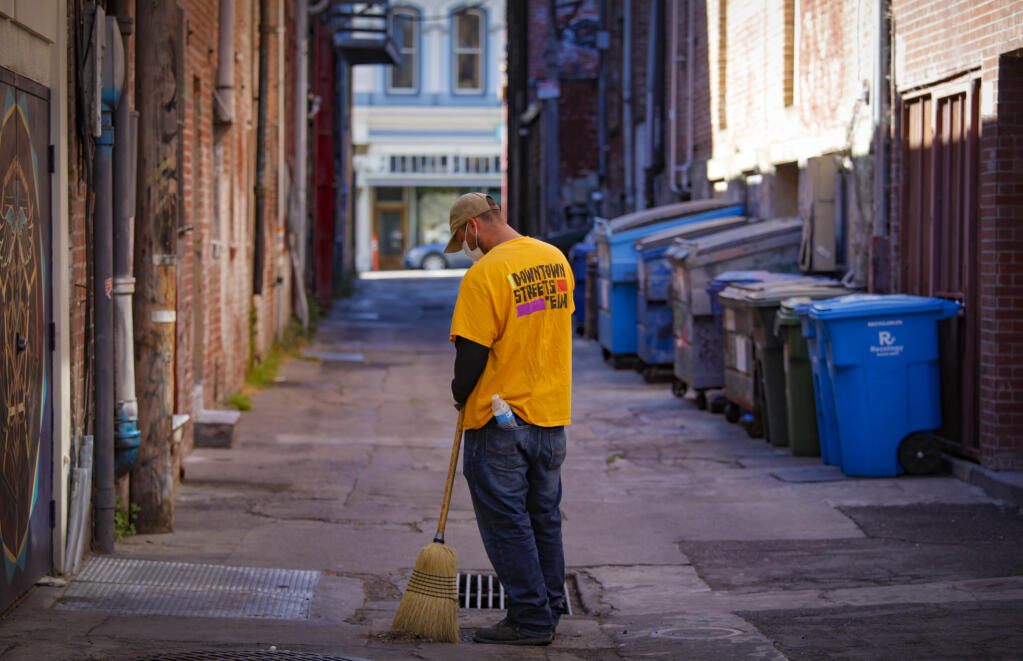 Richard Valencia sweeps along American Alley, next to Helen Putnam Plaza in downtown Petaluma on Monday, June 7, 2021. He volunteers with the Downtown Streets Team, a Bay Area nonprofit contracted by the city of Petaluma to help keep city streets clean and connect homeless residents with services. (CRISSY PASCUAL/ARGUS-COURIER STAFF)