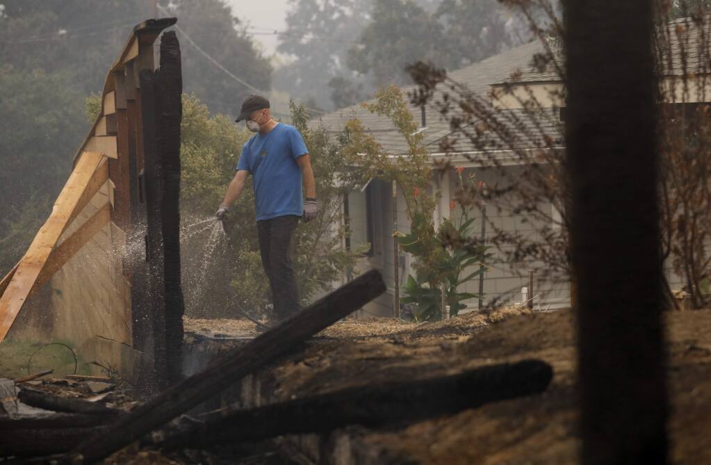 Jim Sillars puts out a fire that burned the fence on his friend's property on Monday, October 9, 2017 in Glen Ellen, California . (BETH SCHLANKER/The Press Democrat)